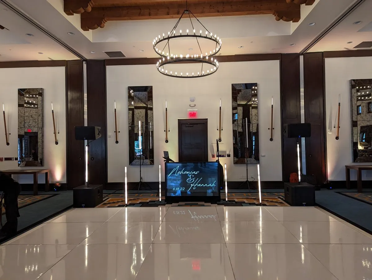 A Cutmaster Music DJ booth set up inside the ballroom at Bishop's Lodge, under a large ring chandelier
