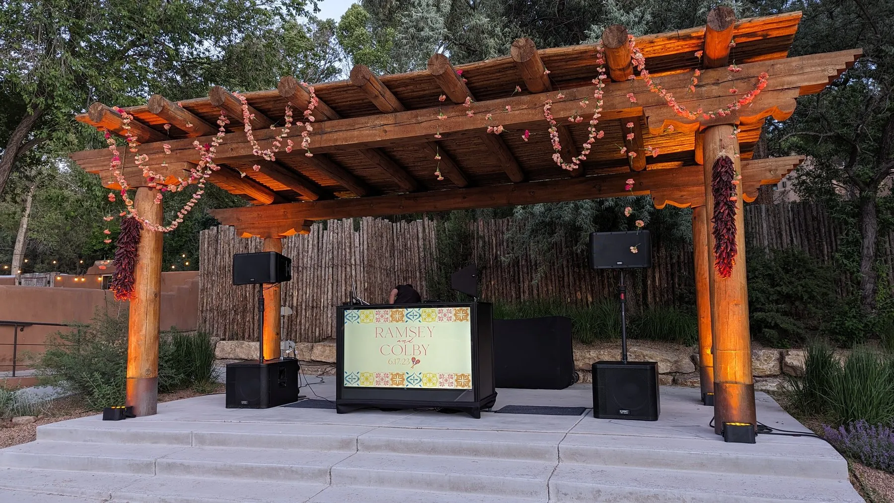 A Cutmaster Music DJ setup under a wooden pergola strung with chile ristras and flower garlands at Bishop's Lodge in Santa Fe