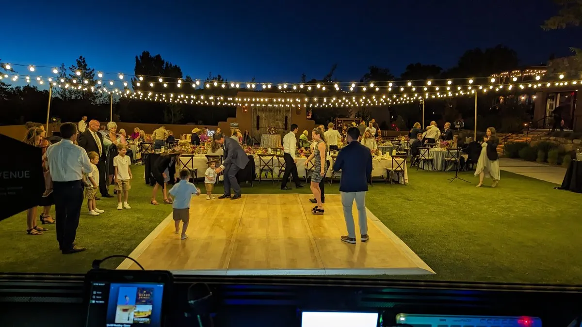 Guests dancing on an outdoor dance floor at Bishop's Lodge at dusk, strung with market lights