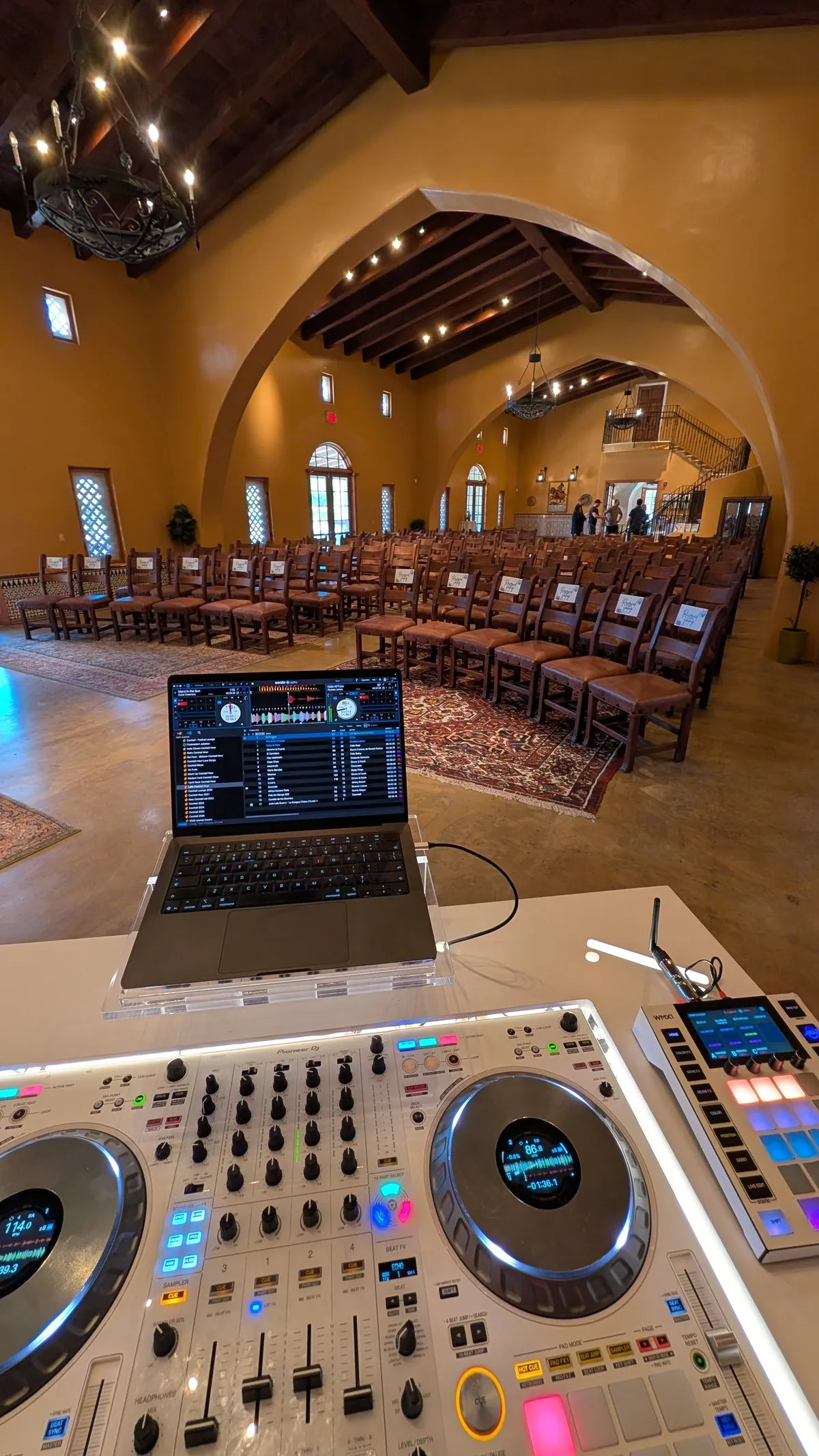 A Cutmaster Music DJ booth set up for a ceremony inside Animante de Rondeña, with guest seating facing the arched stage