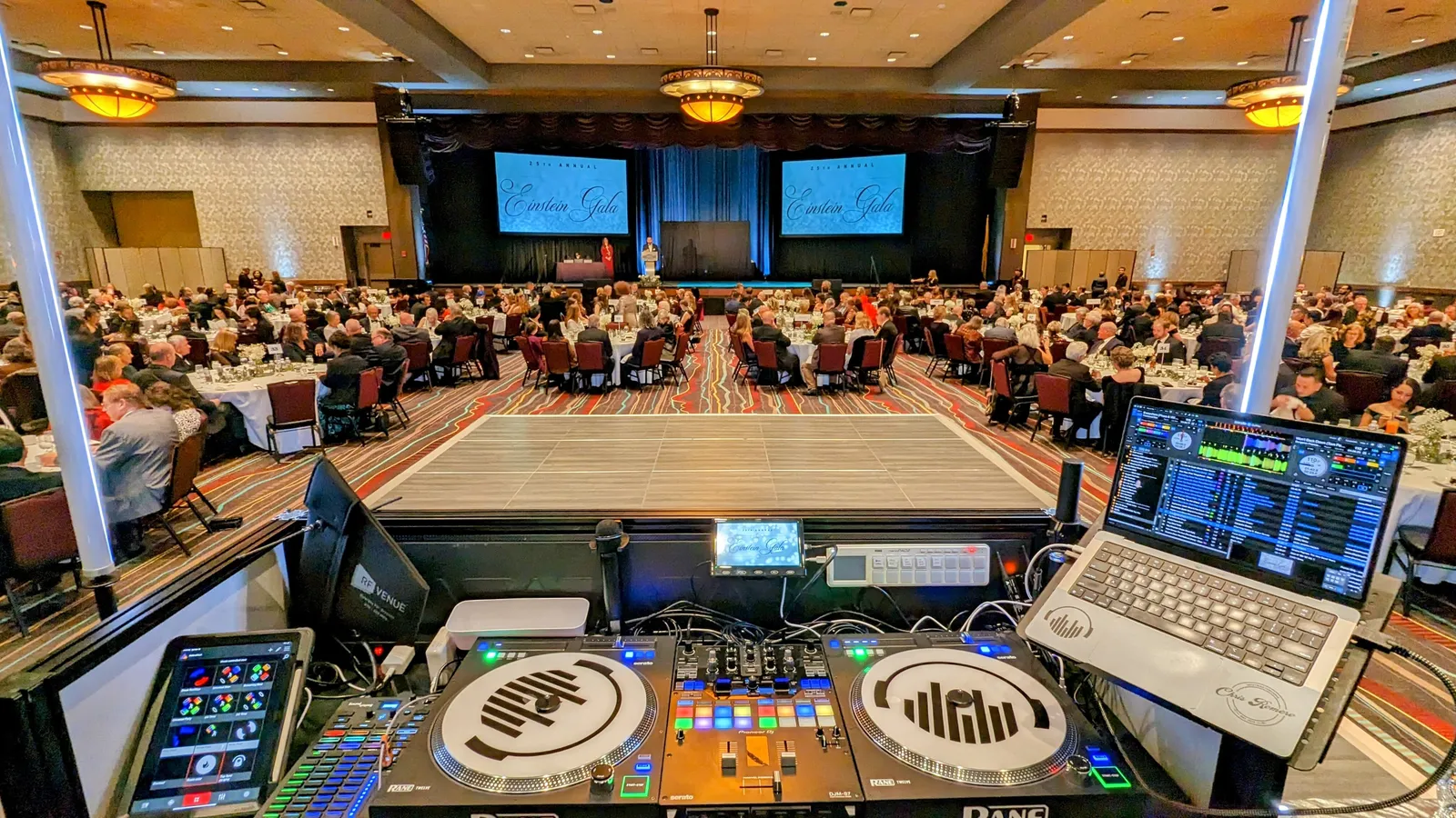 A DJ booth overlooking a ballroom full of guests at a corporate gala