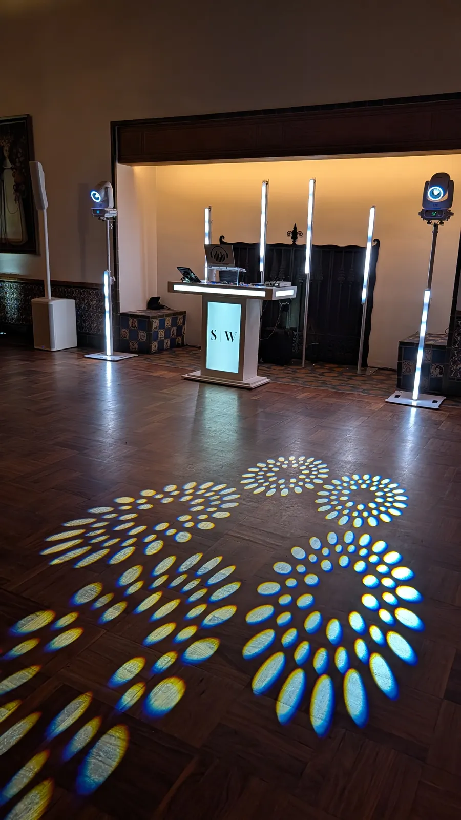 An En Blanc setup in a ballroom, dance floor lit in a matching petal pattern