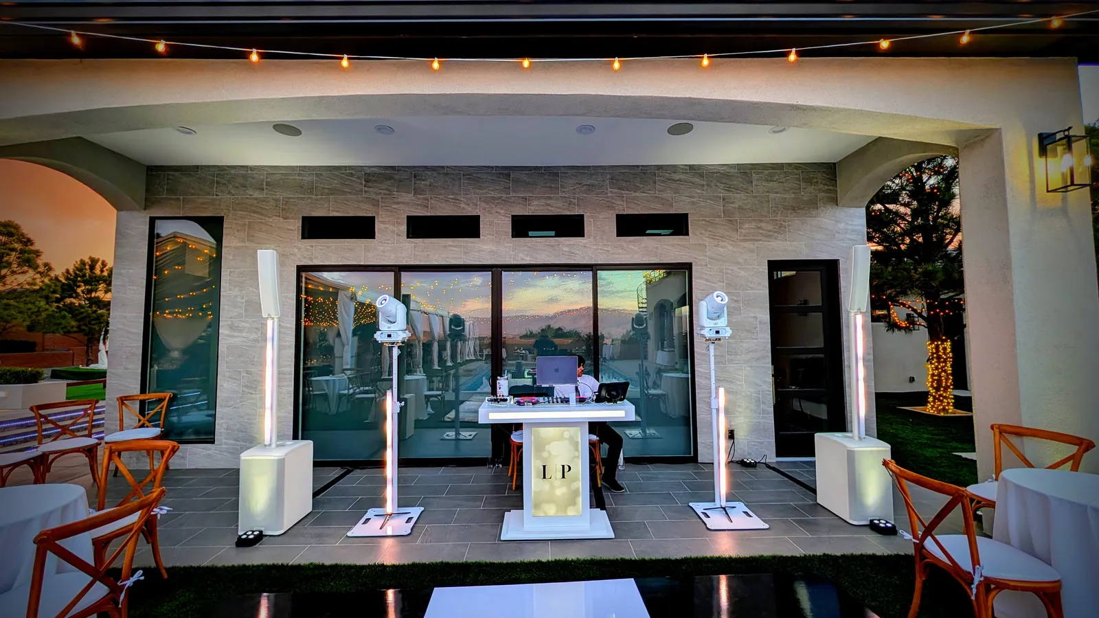 An En Blanc setup on a patio reception at golden hour, booth monogrammed for the couple