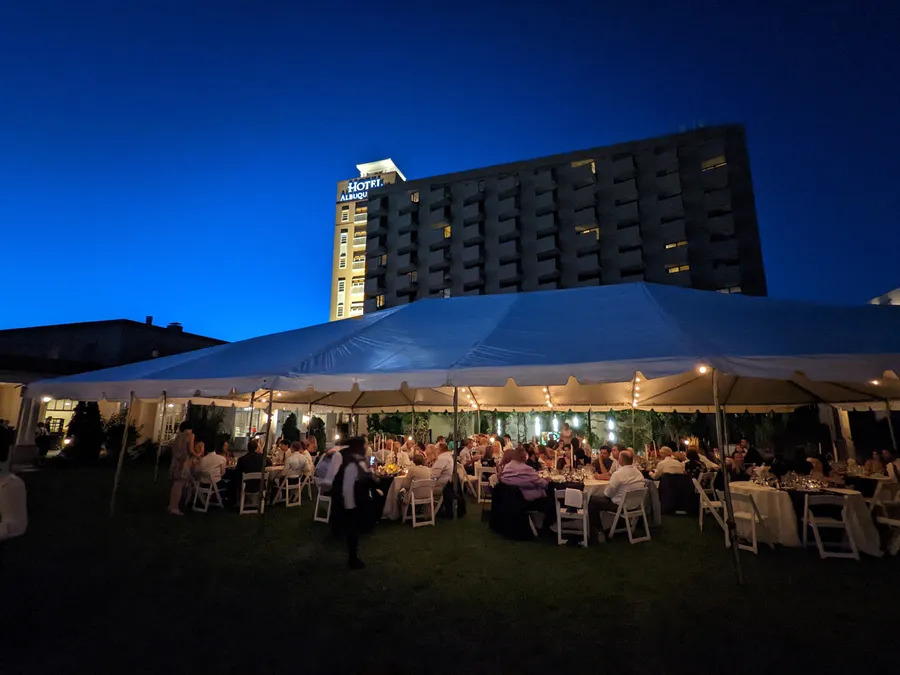 An evening tented reception on the lawn at Hotel Albuquerque, with the hotel tower lit up behind it
