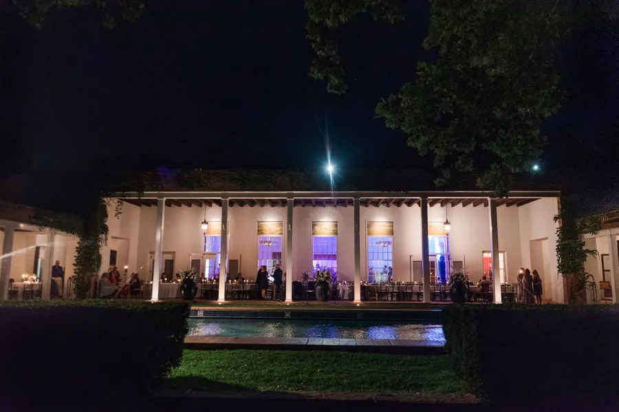 An evening reception under the Portal at Los Poblanos, string-lit tables set along the colonnade beside the pool