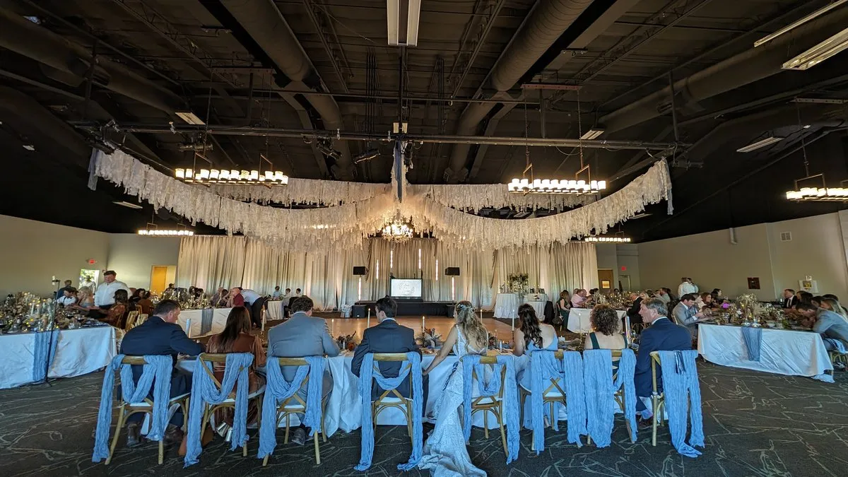 A wedding reception in the Tamaya Ballroom with dusty blue chair drapes and lace ceiling draping